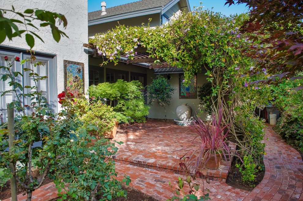 Immagine di un patio o portico classico di medie dimensioni e dietro casa con un giardino in vaso, pavimentazioni in mattoni e una pergola