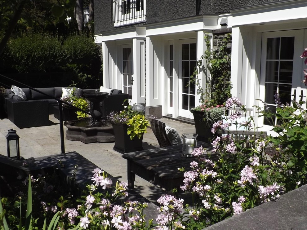 This is an example of a large victorian back patio in Vancouver with a water feature and natural stone paving.