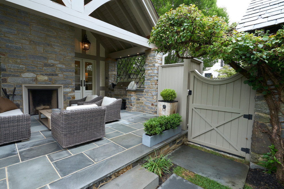 Example of a large classic backyard stone patio design in Philadelphia with a fireplace and a roof extension