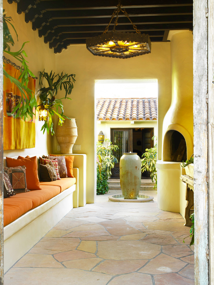 Photo of a mediterranean courtyard patio in Los Angeles with a roof extension, a fire feature and natural stone paving.