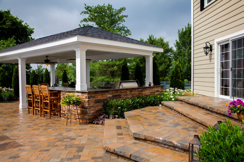 Idée de décoration pour une grande terrasse arrière tradition avec des pavés en pierre naturelle, une cuisine d'été et un gazebo ou pavillon.