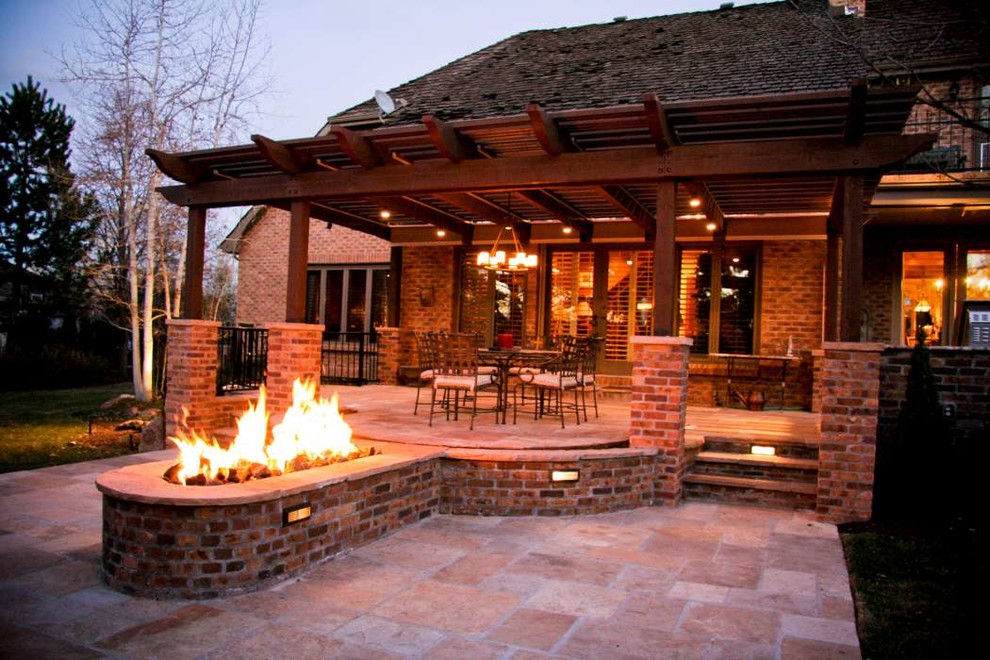 Modelo de patio clásico grande en patio trasero con brasero, adoquines de piedra natural y pérgola