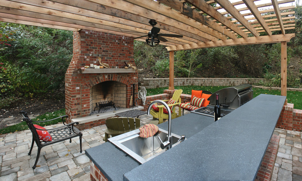 Immagine di un patio o portico tradizionale di medie dimensioni e dietro casa con pavimentazioni in cemento, una pergola e un focolare