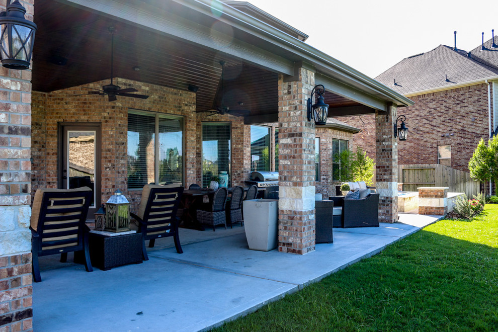 Photo of a large classic back patio in Houston with a fire feature, concrete slabs and a roof extension.