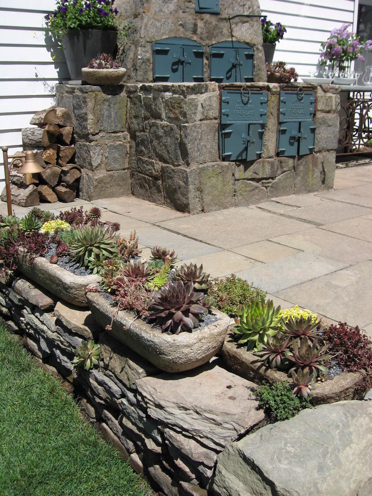 Foto di un piccolo patio o portico tradizionale dietro casa con un giardino in vaso e pavimentazioni in pietra naturale