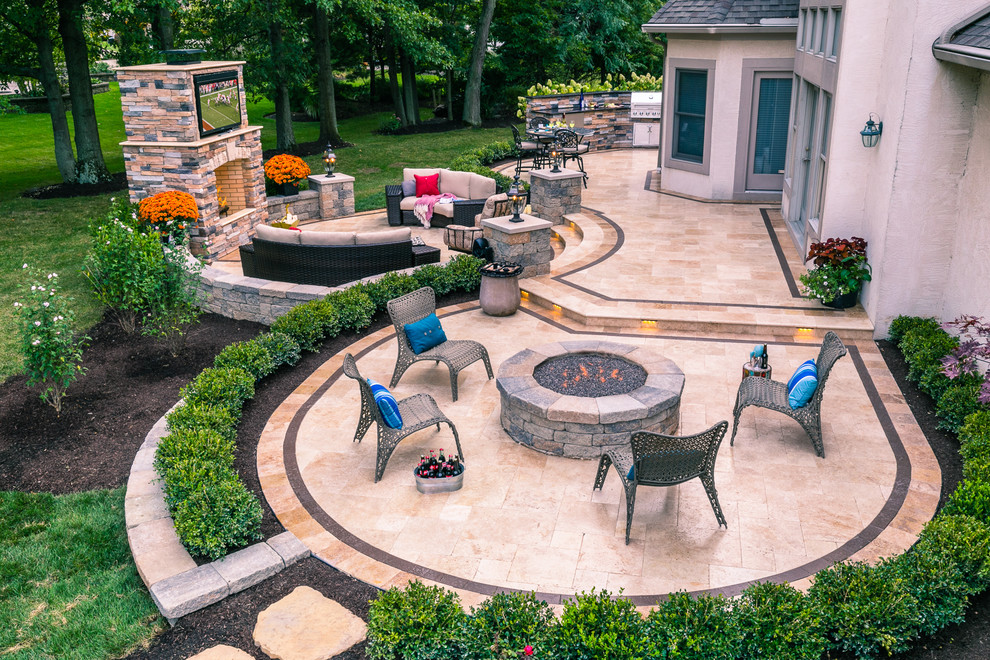 На фото: огромный двор на заднем дворе в классическом стиле с местом для костра и покрытием из каменной брусчатки с