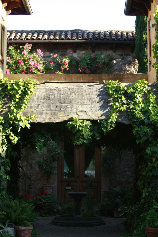 Immagine di un patio o portico mediterraneo in cortile con pavimentazioni in pietra naturale e una pergola