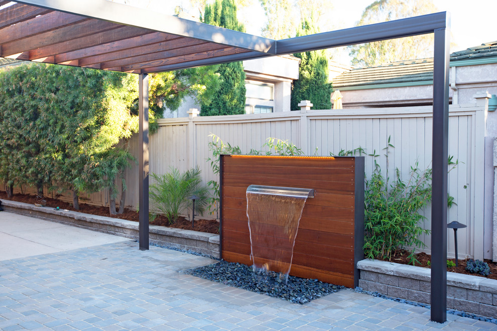 Inspiration for a small contemporary courtyard concrete paver patio fountain remodel in San Luis Obispo with a pergola