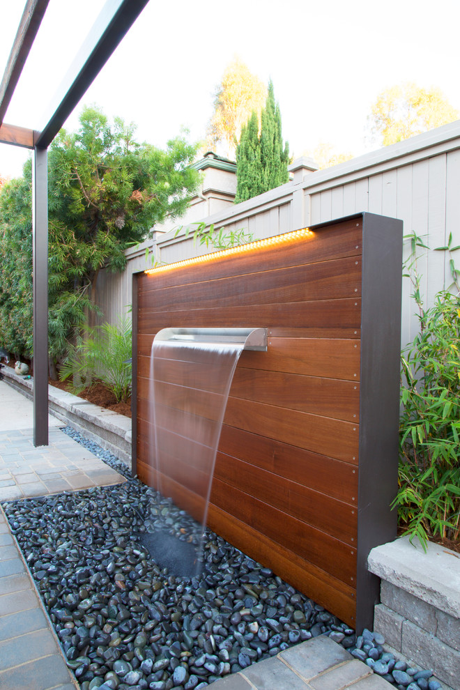 Patio fountain - small contemporary courtyard concrete paver patio fountain idea in San Luis Obispo with a pergola