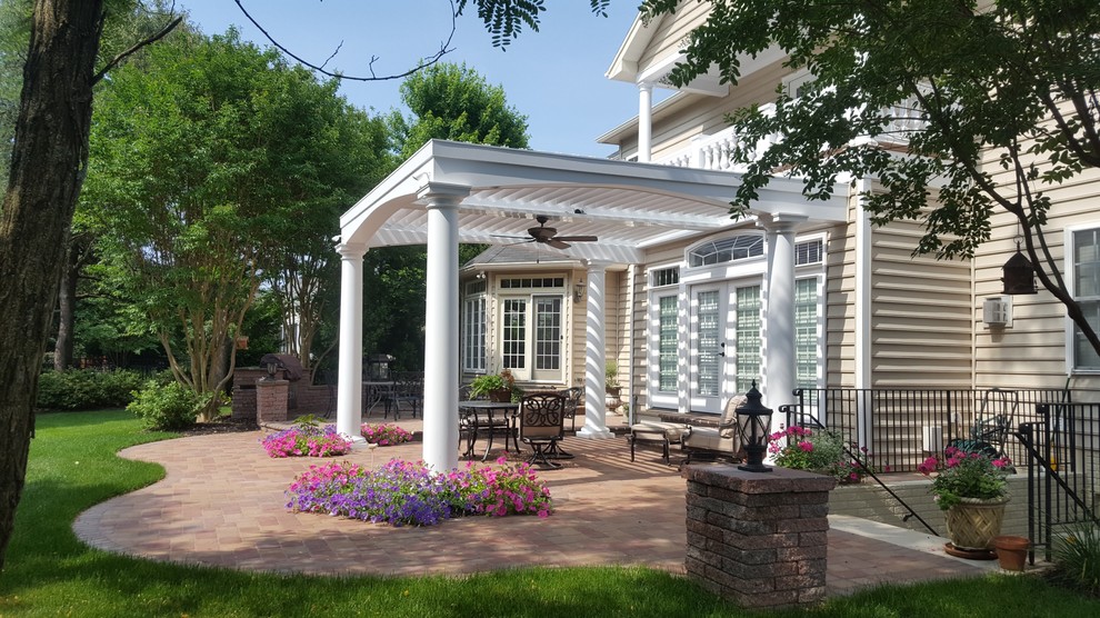 Example of a mid-sized classic backyard brick patio design in DC Metro with a pergola