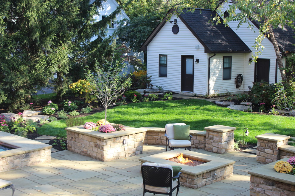 Foto di un patio o portico classico dietro casa con un focolare, nessuna copertura e pavimentazioni in pietra naturale