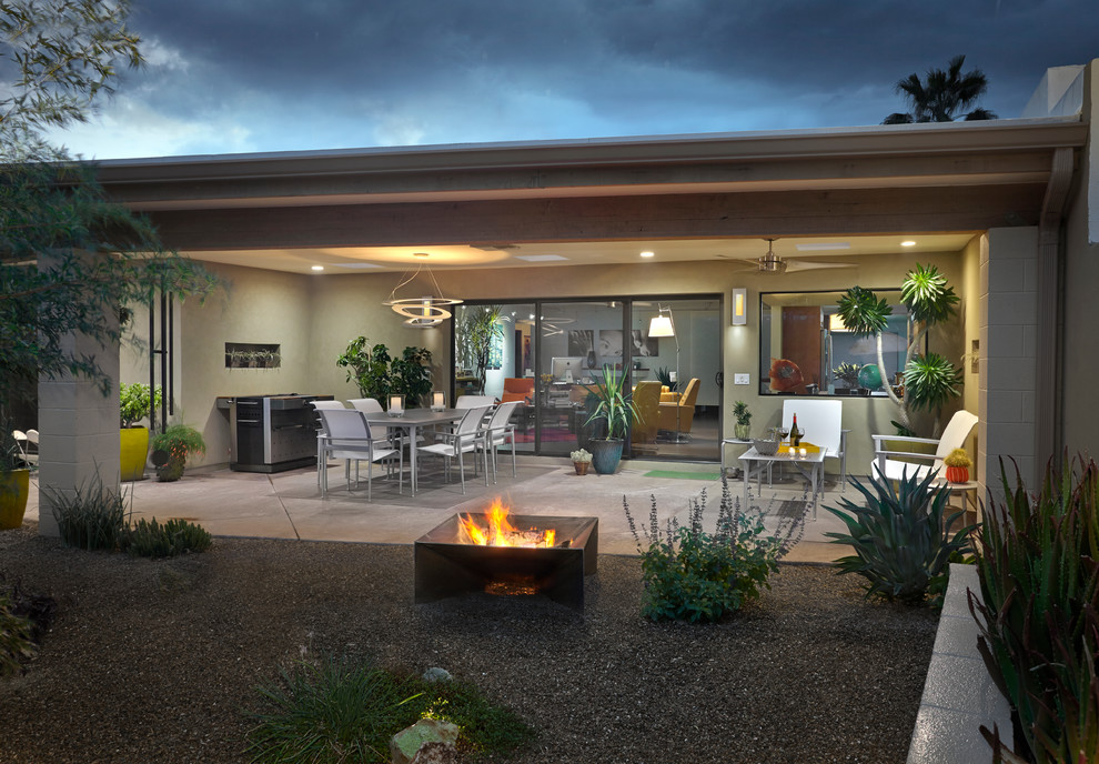 Foto di un patio o portico stile americano dietro casa con un focolare, lastre di cemento e un tetto a sbalzo