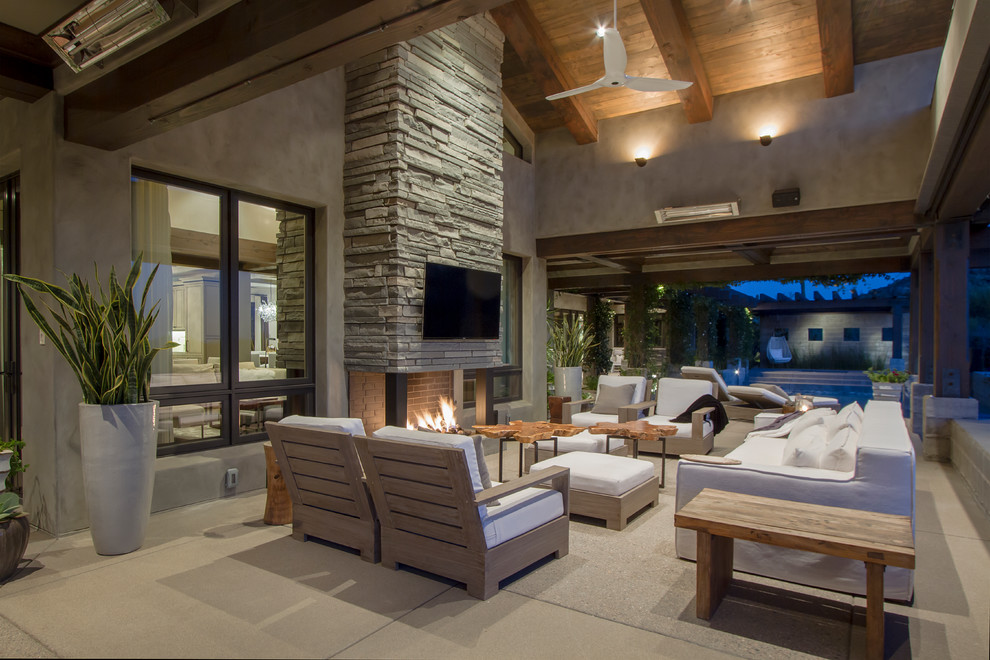 Contemporary patio in Phoenix with concrete slabs, a roof extension and a fireplace.
