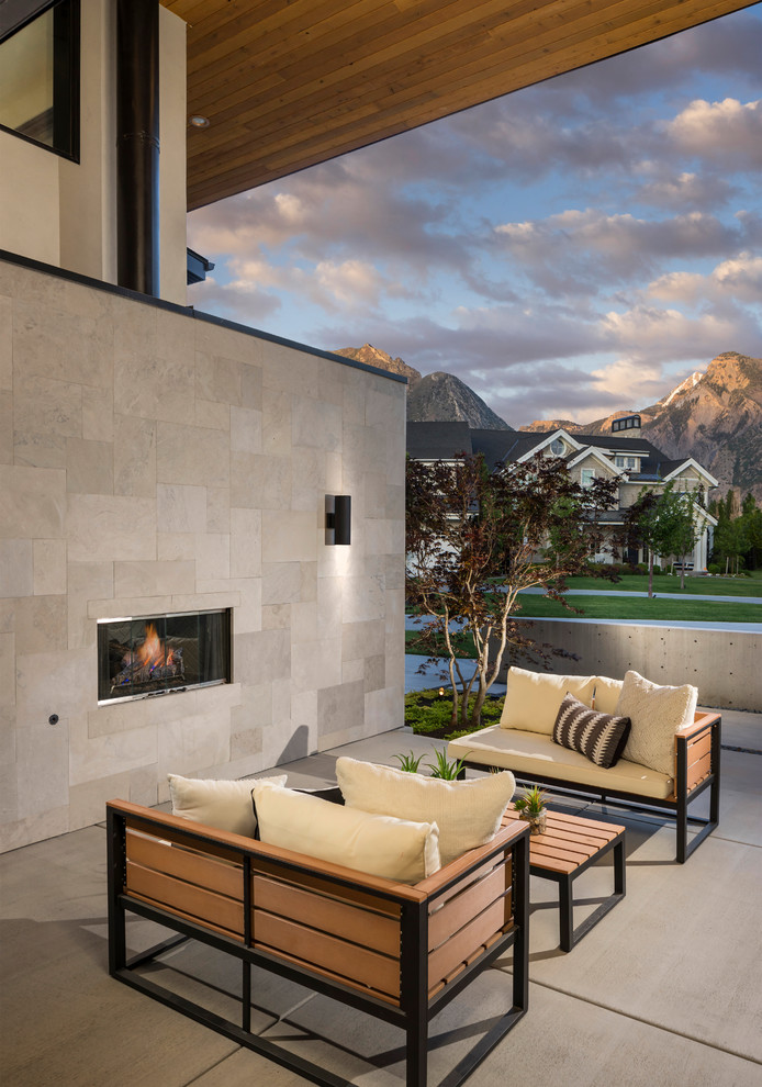 Geräumiger, Überdachter Moderner Patio mit Betonplatten und Kamin in Salt Lake City