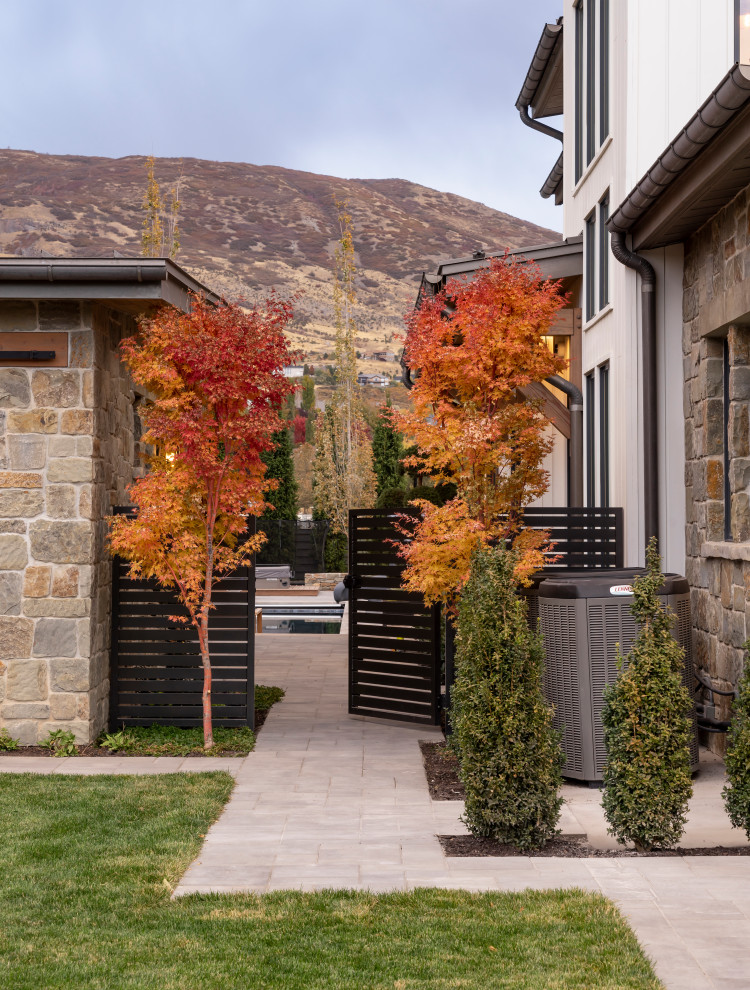 This is an example of a large country back patio in Salt Lake City with a fire feature, concrete paving and a pergola.