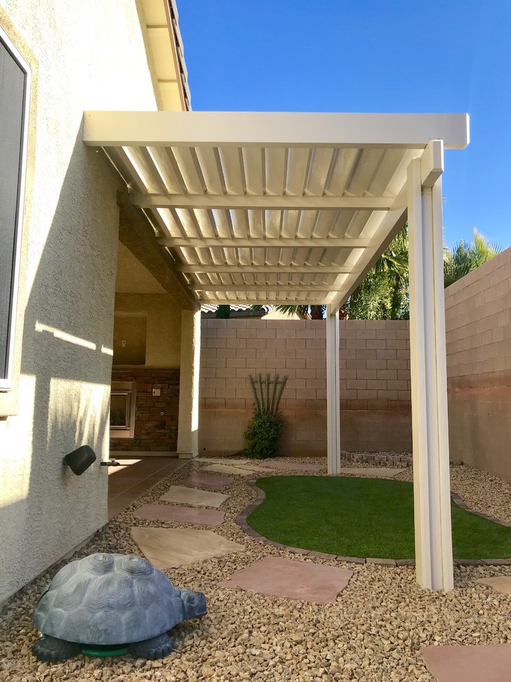 This is an example of an expansive nautical back patio in Las Vegas with an outdoor kitchen, stamped concrete and an awning.