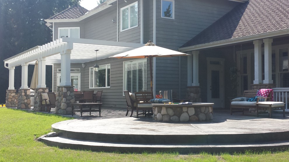 Large arts and crafts backyard stamped concrete patio kitchen photo in Seattle with a pergola