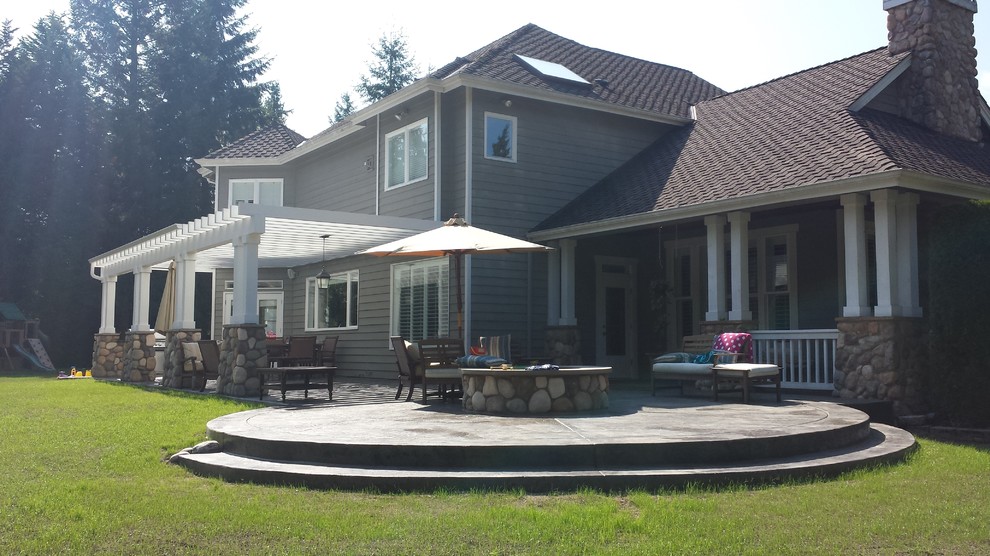 This is an example of a large traditional back patio in Seattle with an outdoor kitchen, stamped concrete and a pergola.