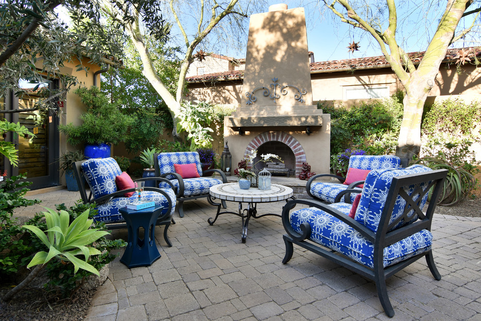Photo of a medium sized mediterranean back patio in Phoenix with a fireplace, natural stone paving and no cover.