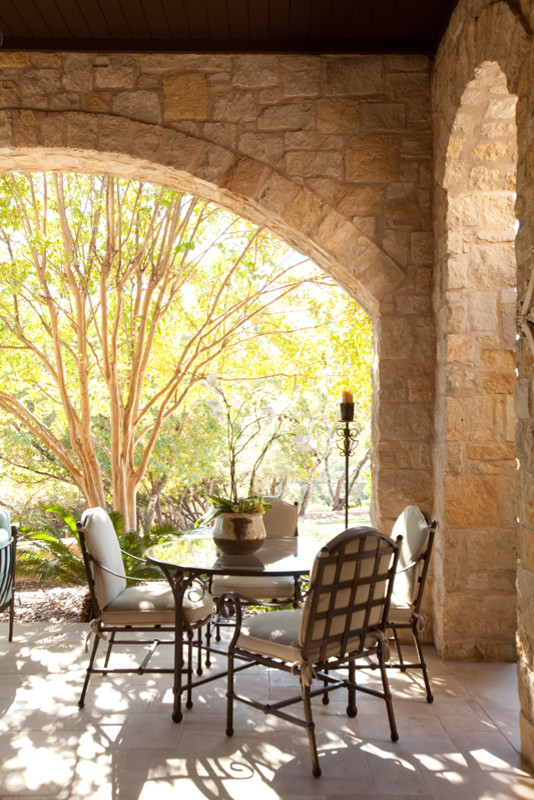 Inspiration for a large mediterranean backyard stone patio kitchen remodel in Austin with a roof extension