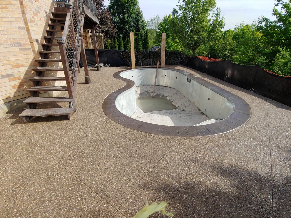 This is an example of a medium sized modern back patio in Toronto with a water feature and stamped concrete.