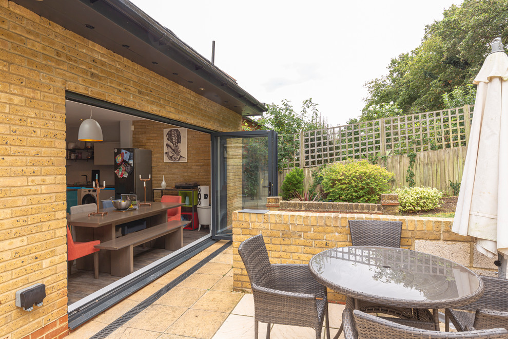 Modelo de patio actual de tamaño medio en patio trasero con cocina exterior, adoquines de piedra natural y toldo