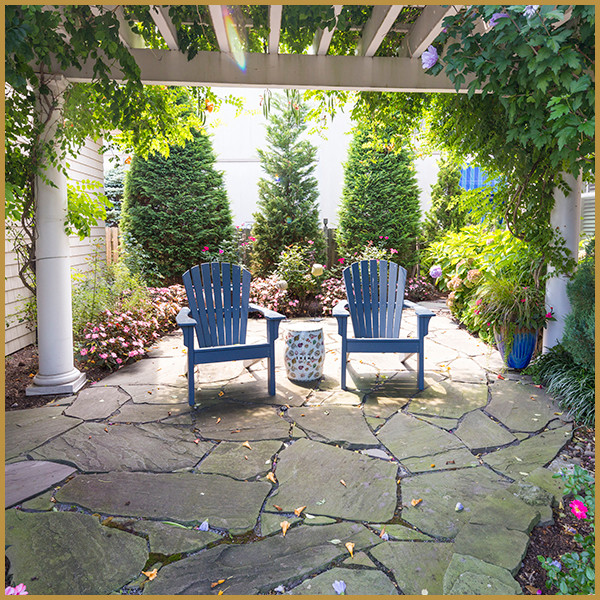 Example of a large beach style backyard concrete paver patio design in New York with a pergola
