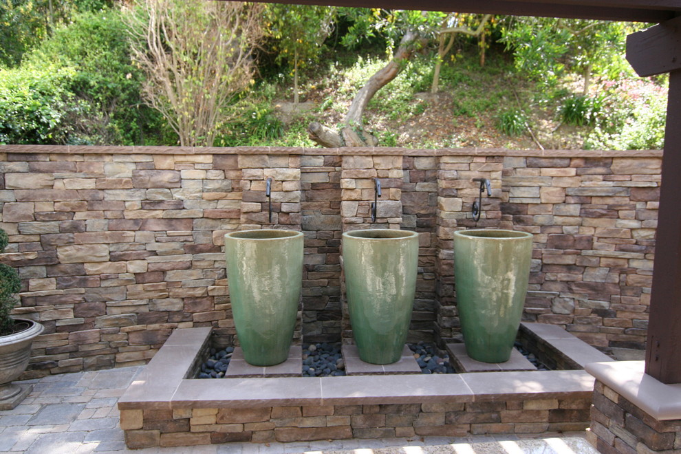 Foto de patio clásico de tamaño medio en patio trasero con fuente, adoquines de hormigón y pérgola