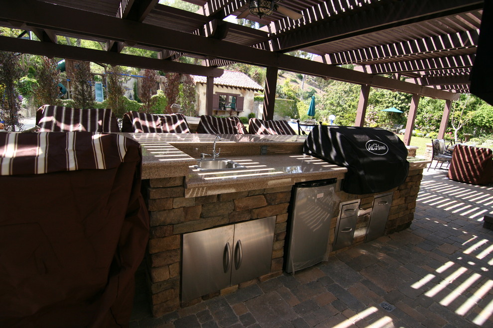 Inspiration for a mid-sized timeless backyard concrete paver patio kitchen remodel in Orange County with a pergola
