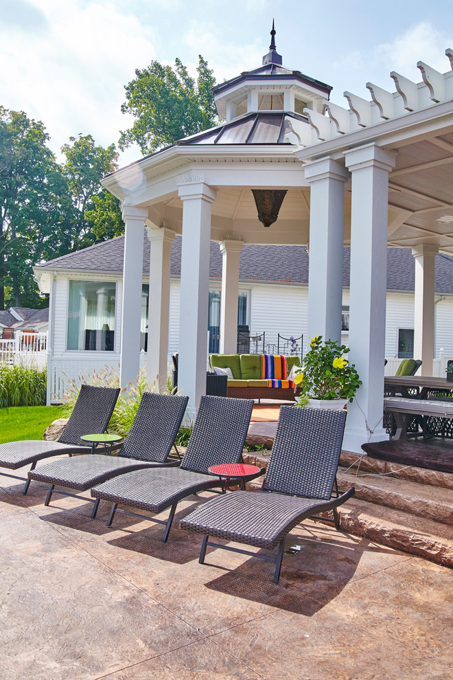 Diseño de patio de estilo americano de tamaño medio en patio trasero con adoquines de piedra natural y cenador