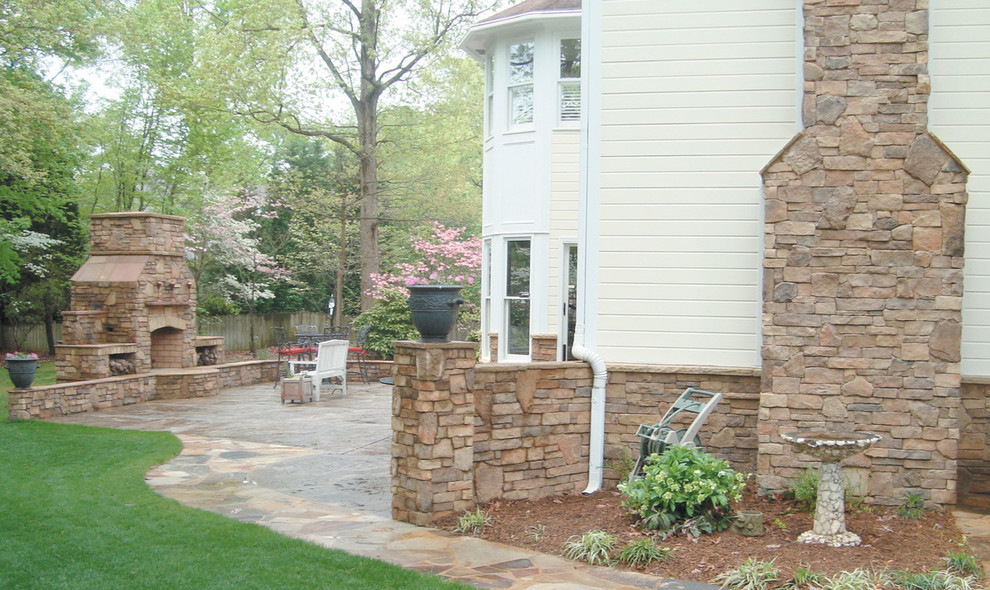 Example of a mid-sized classic backyard stone patio design in Toronto with a fire pit and no cover