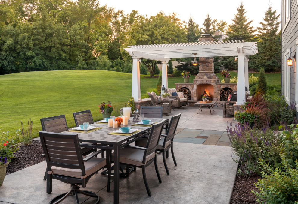 Imagen de patio clásico renovado con chimenea, losas de hormigón y pérgola