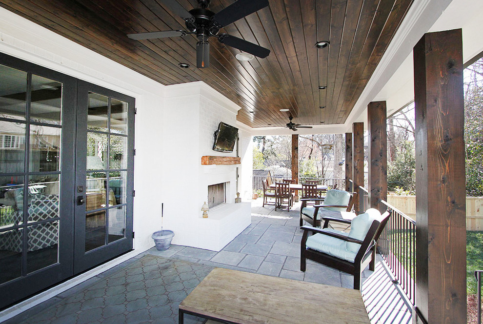 Immagine di un patio o portico chic di medie dimensioni e dietro casa con pavimentazioni in pietra naturale e un tetto a sbalzo