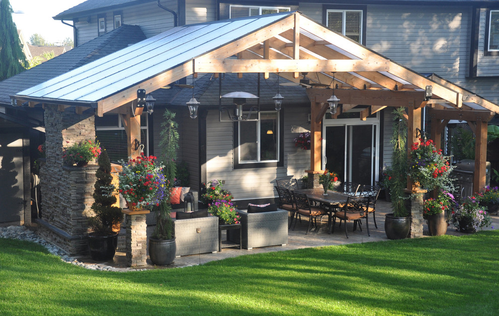 Large traditional back patio in Vancouver with a fire feature, natural stone paving and a pergola.