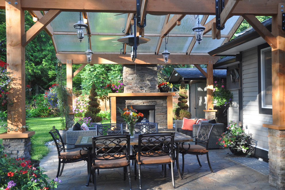 Design ideas for a large classic back patio in Vancouver with a fire feature, natural stone paving and a pergola.