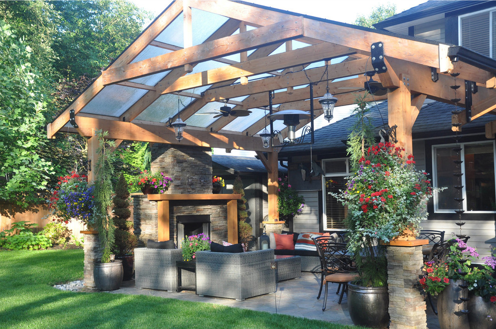 Photo of a large traditional back patio in Vancouver with a fire feature, natural stone paving and a pergola.