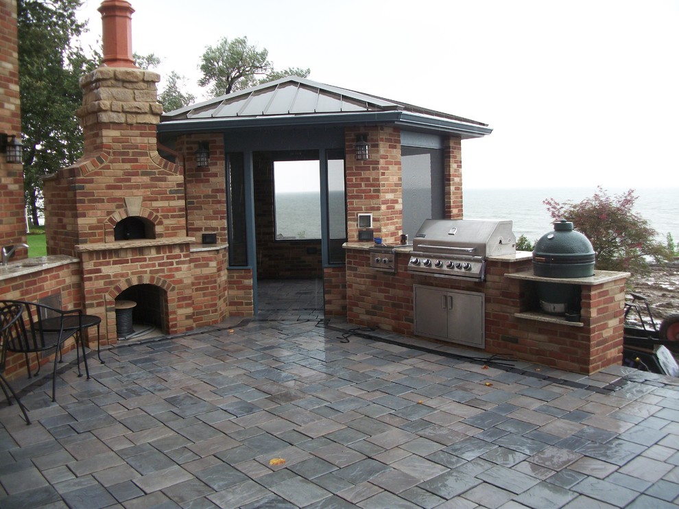 Cette photo montre une terrasse arrière tendance de taille moyenne avec une cuisine d'été, des pavés en pierre naturelle et un gazebo ou pavillon.