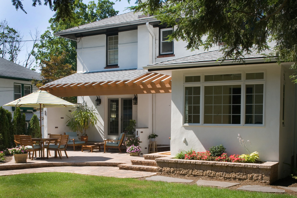 Esempio di un patio o portico tradizionale di medie dimensioni e dietro casa con pavimentazioni in mattoni e un tetto a sbalzo