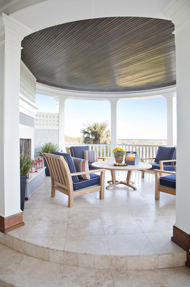 Exemple d'une terrasse bord de mer avec un foyer extérieur et une extension de toiture.