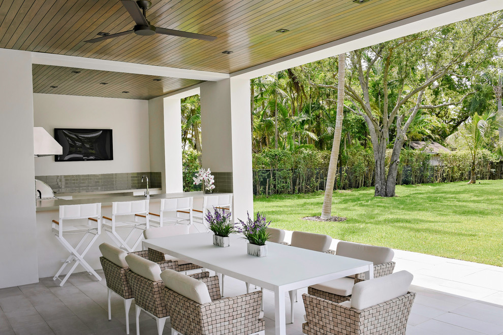 На фото: двор на заднем дворе в современном стиле с летней кухней, покрытием из плитки и навесом с