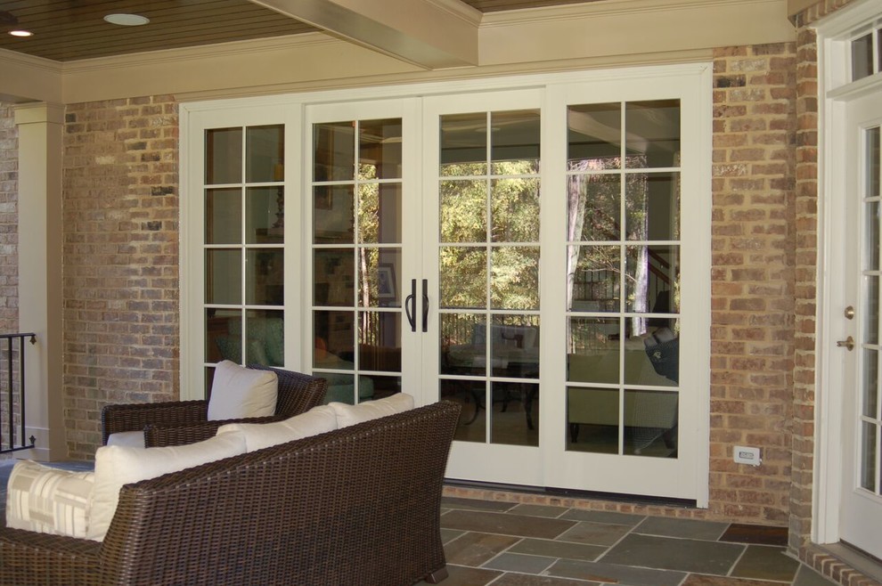Immagine di un patio o portico chic di medie dimensioni e dietro casa con un focolare, graniglia di granito e un tetto a sbalzo