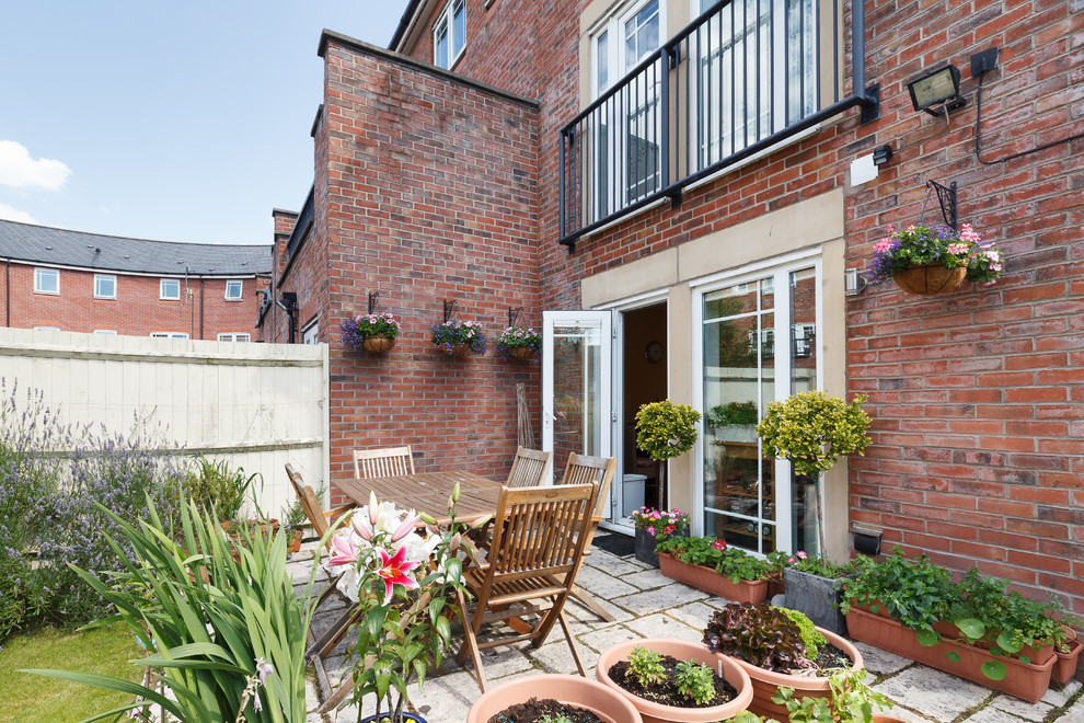 This is an example of a classic back patio in Manchester with a potted garden, concrete paving and no cover.