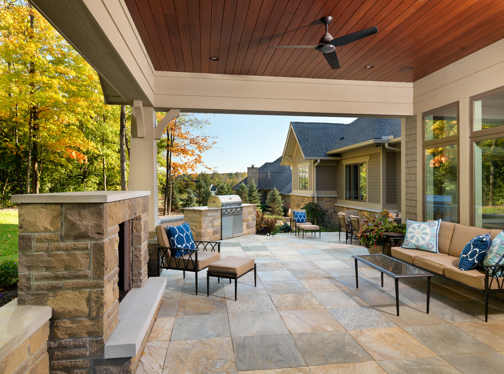 Cette photo montre une grande terrasse arrière craftsman avec un foyer extérieur, du carrelage et une extension de toiture.