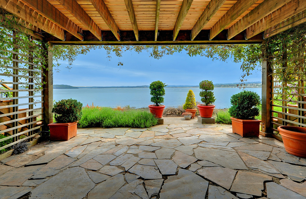 Example of a classic stone patio design in Seattle with a roof extension