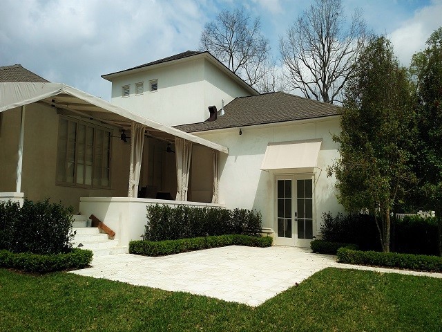 Photo of a medium sized classic back patio in New Orleans with natural stone paving and an awning.