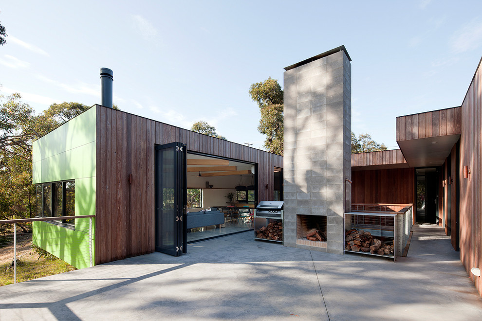 Bild på en stor minimalistisk gårdsplan, med en eldstad och betongplatta