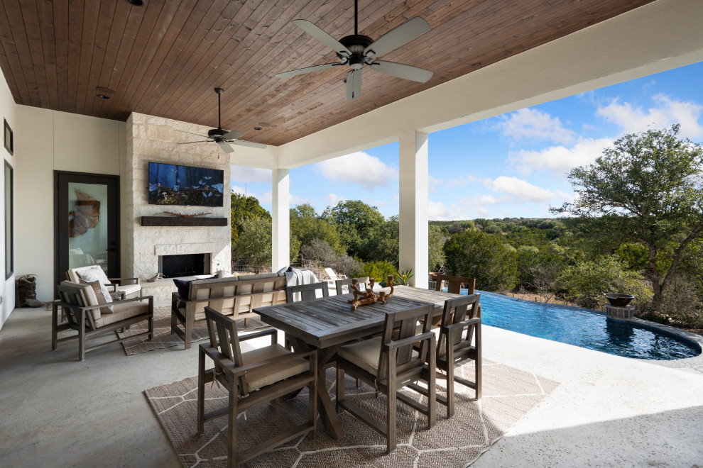Inspiration for a modern backyard concrete patio remodel in Austin with a fireplace and a roof extension