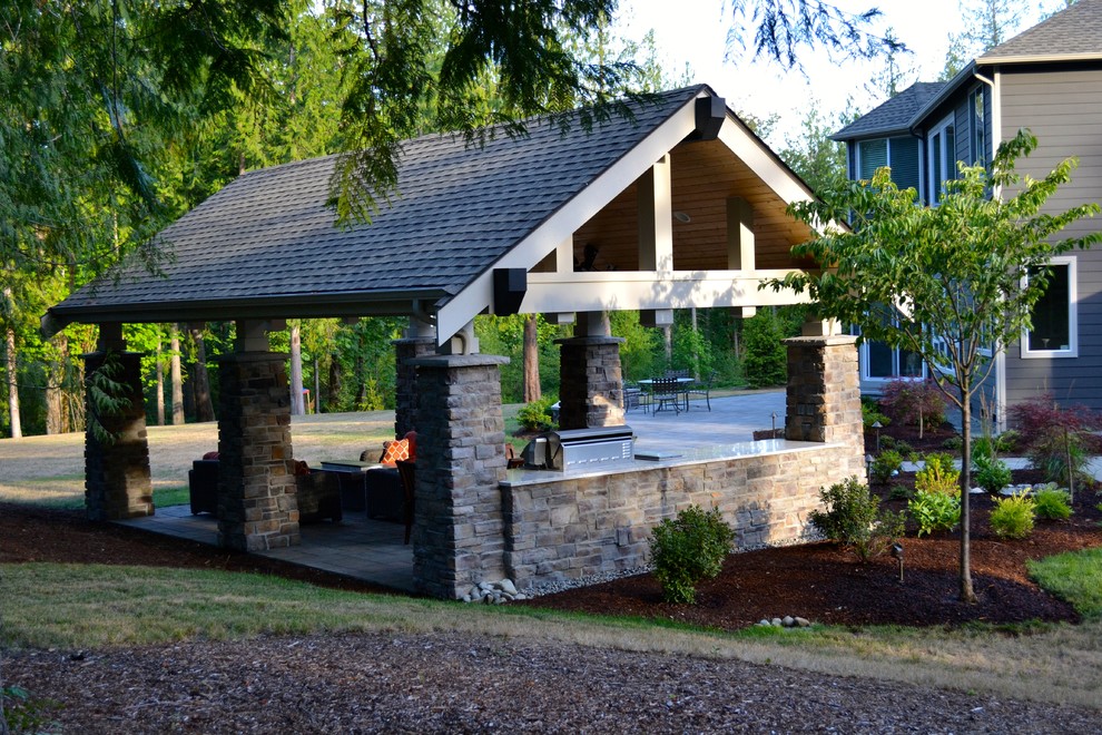 Réalisation d'une grande terrasse arrière design avec une cuisine d'été, des pavés en béton et une extension de toiture.