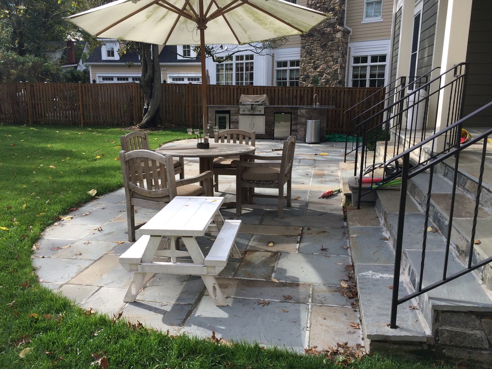 This is an example of a small classic back patio in DC Metro with an outdoor kitchen, natural stone paving and no cover.