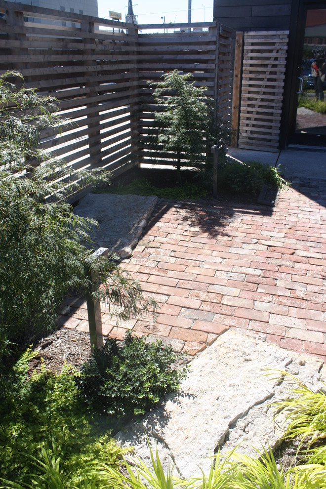 Esempio di un piccolo patio o portico eclettico in cortile con pavimentazioni in mattoni